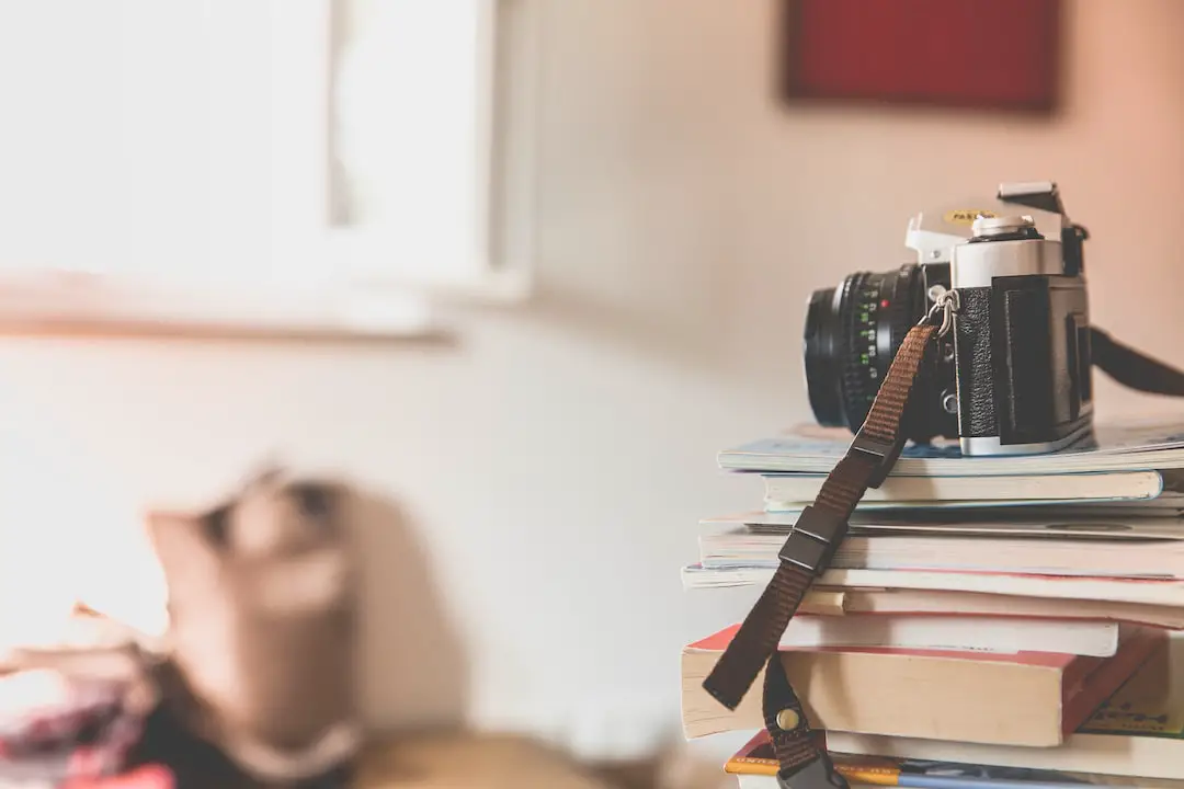 black film camera on top of piled books inside well lighted room