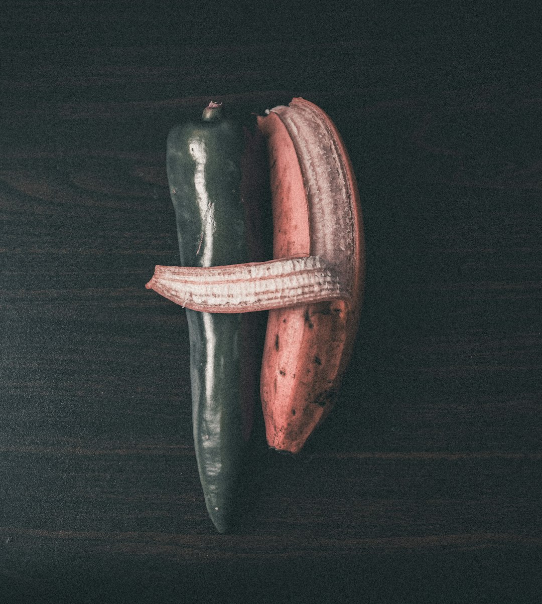 a couple of green and red peppers sitting on top of a wooden table