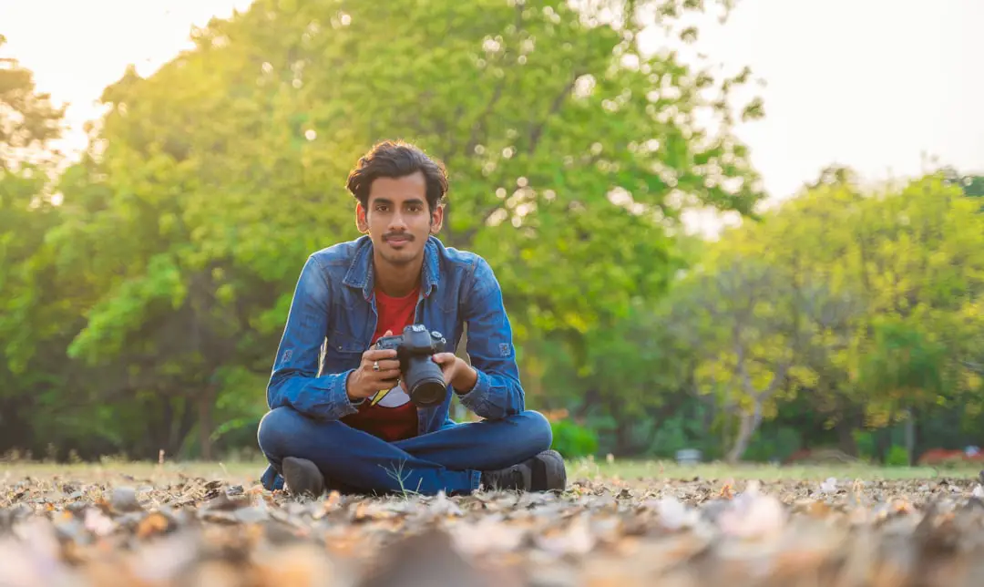 a man sitting on the ground holding a cup and looking at the camera