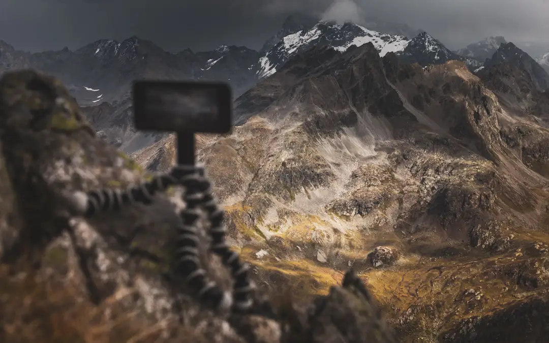 Timelapsing Austrian mountains. by Camera Brands black wooden cross on brown grass field near mountain during daytime