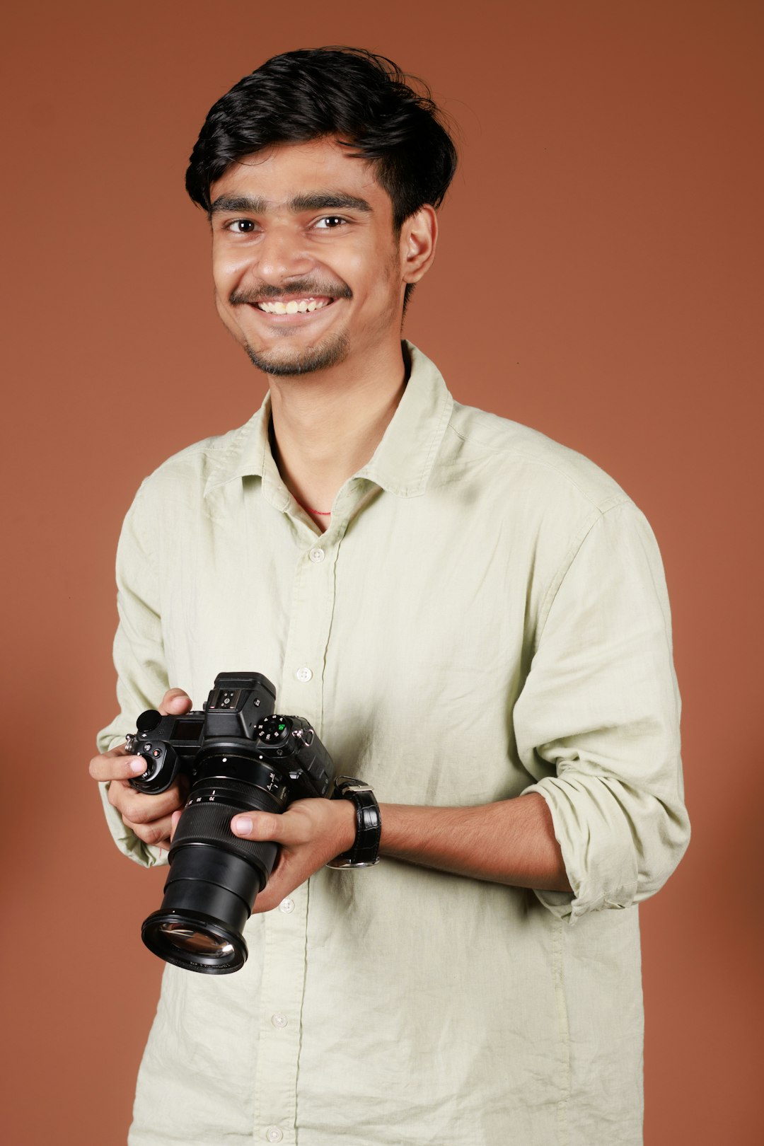 a man holding a camera and smiling at the camera