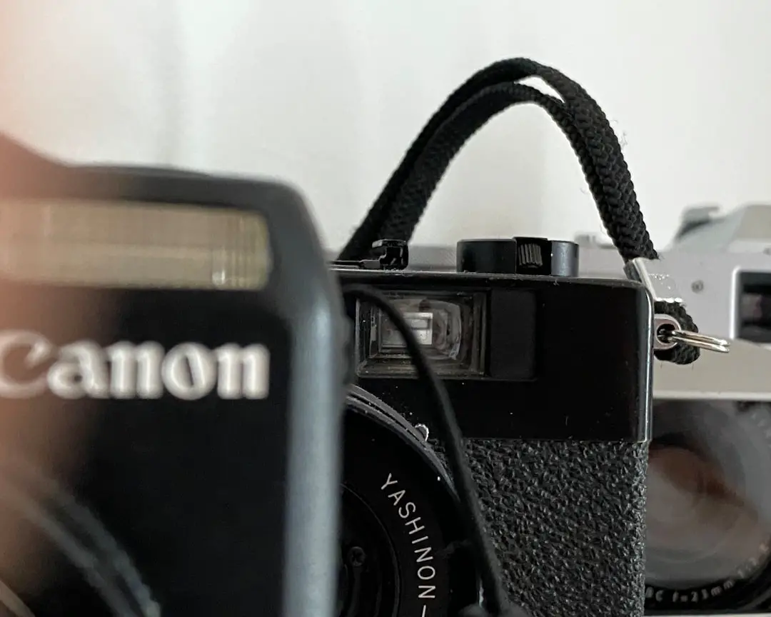 a black camera and a silver camera on a table